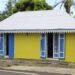 Case créole jaune aux volets bleus et toit métallique à La Réunion