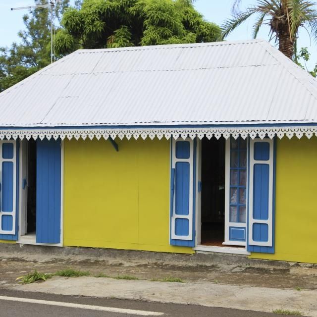 Case créole jaune aux volets bleus et toit métallique à La Réunion