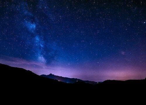 Voie lactée au-dessus d’un relief montagneux sous un ciel nocturne