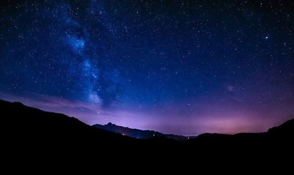 Voie lactée au-dessus d’un relief montagneux sous un ciel nocturne